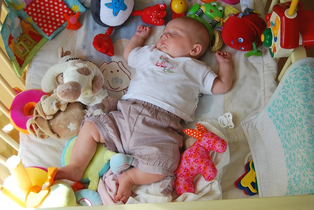 miminko spící v postýlce s hračkami